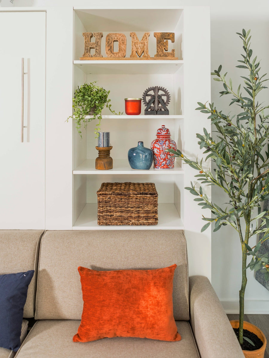 Living room with a beige sofa, orange pillow, and decorative shelves.