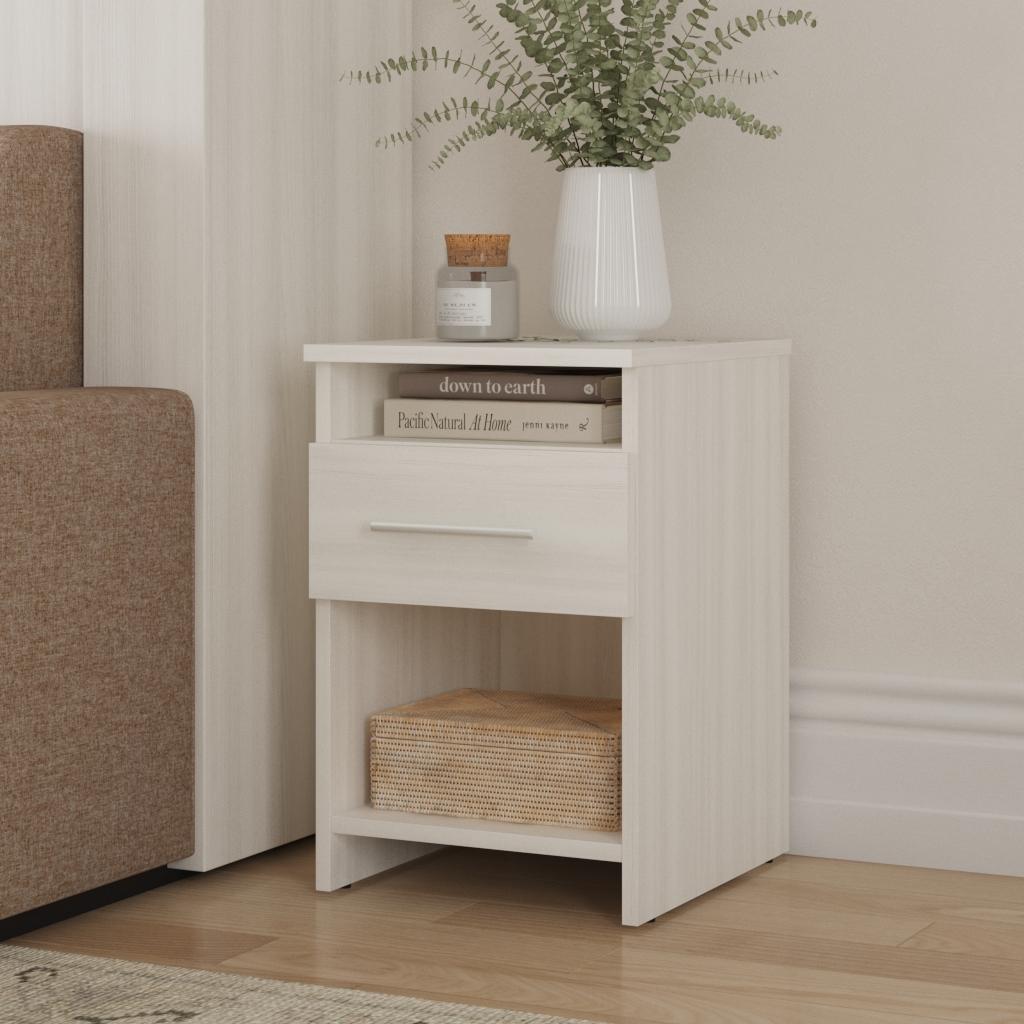 White nightstand with a drawer, books, and a vase with plants in a room setting.