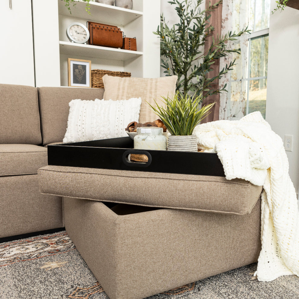 beige ottoman with plant and blanket