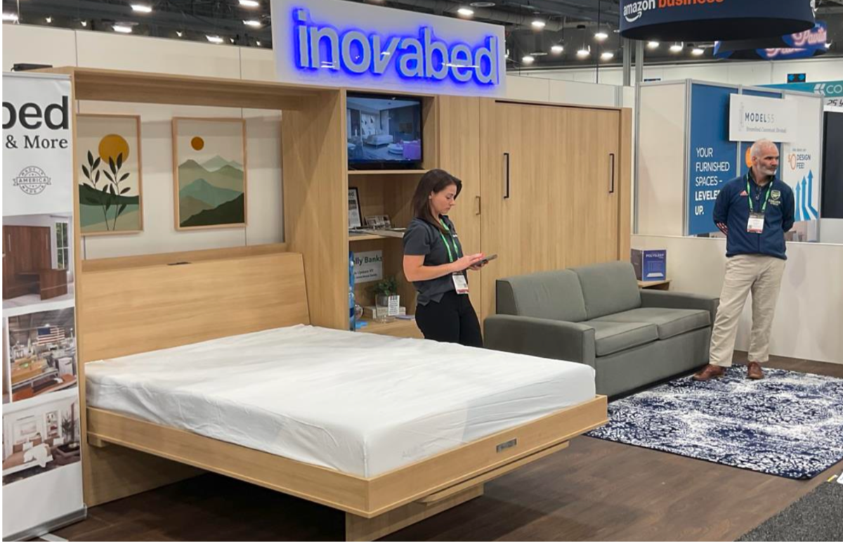 Innovabed display at a trade show with a woman and man examining a bed unit.