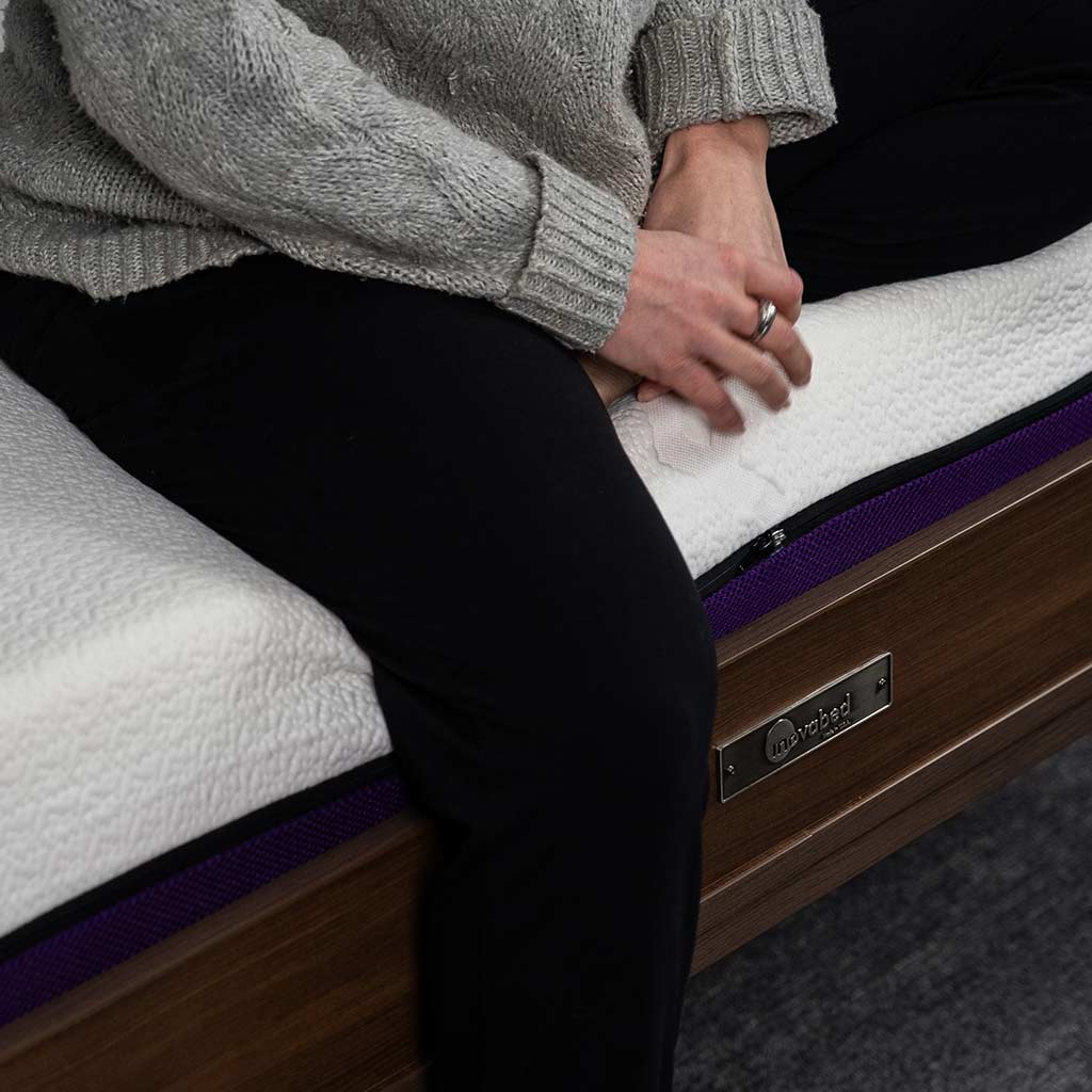 female sitting on Polysleep mattress on edge of Inovabed 