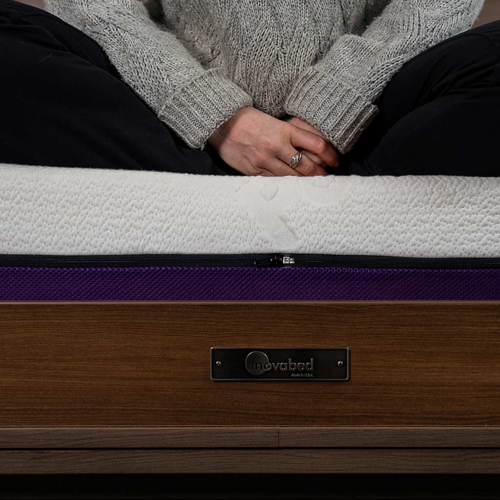 female cross legged at the edge of Inovabed wall bed on top of Polysleep 10" mattress