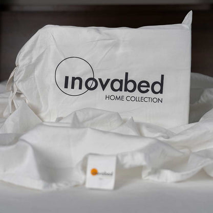 Detail shot of the Inovabed Home Collection - Queen Sheet Set packaging on top of a crumpled top sheet.