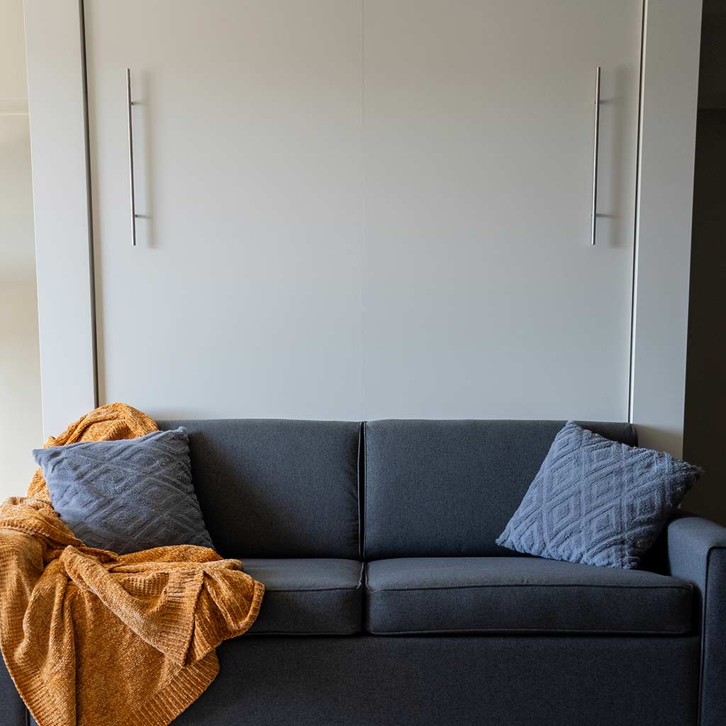 Wall Bed with Sofa freestanding snug against the wall. Sofa is grey and the wall bed cabinet is white.