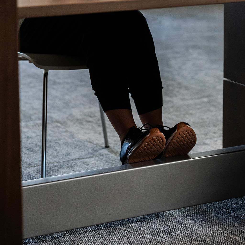 Feet in sneakers resting on the footrest of the Wall Bed with Table